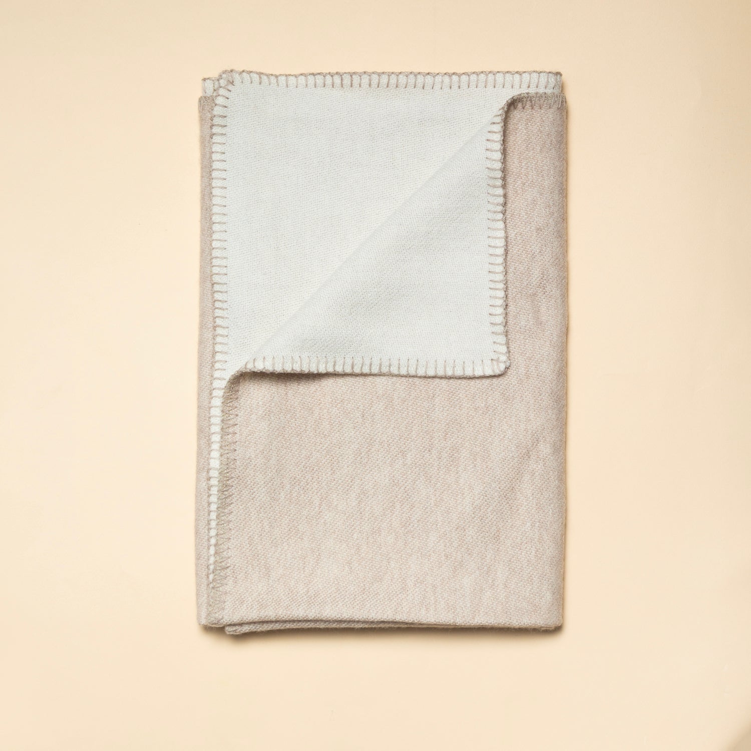 Lyxig merinoullfilt från Skogen Baby i beige och vit, mjuk och värmande för bebisar och småbarn.